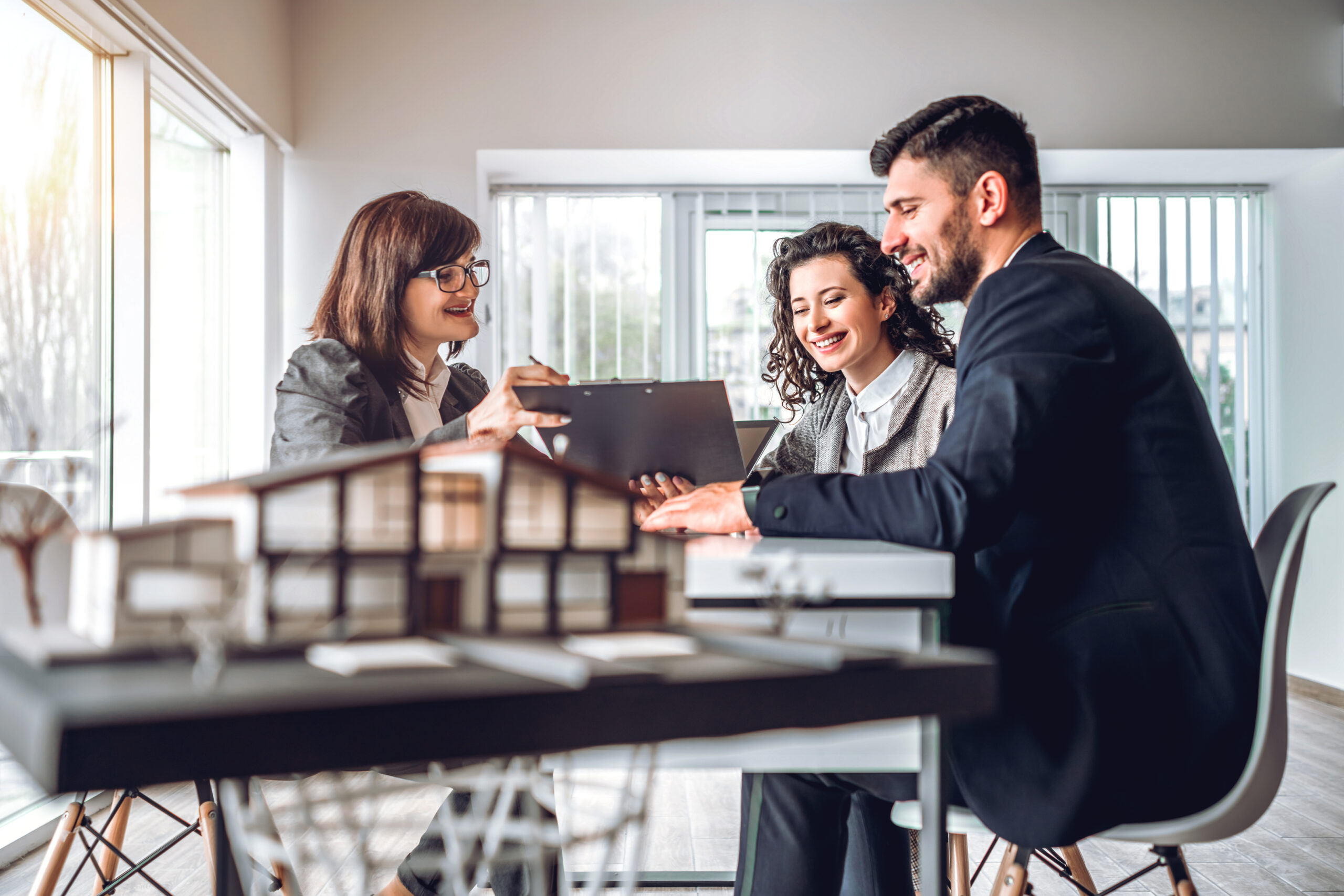 Side view image of young happy family sitting in consulting office, making property purchase. Mature realtor helping business couple do financial investment. Installment payment, mortgage loan concept; Shutterstock ID 1548562148; Purchase Order: comps; Job: ; Client/Licensee: ; Other: